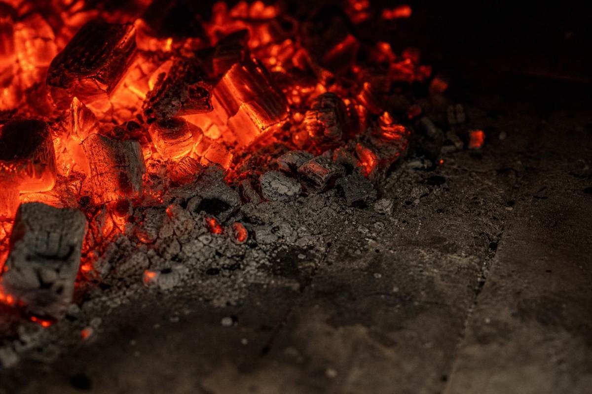 A bed of glowing hardwood embers and ash on the oven floor